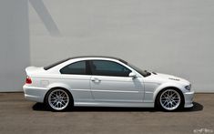 a white car parked in front of a wall