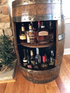 a wooden barrel filled with liquor bottles next to a christmas tree