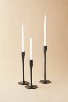 three black candles are standing next to each other with white candles in the middle and one candle between them