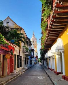 an empty street lined with colorful buildings in the middle of town on a sunny day