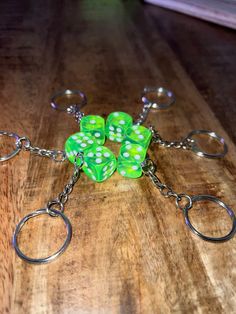 four green dices sitting on top of a wooden table next to two silver rings