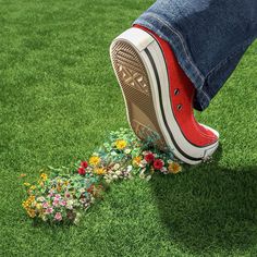 a person standing on top of a green field with flowers coming out of the ground