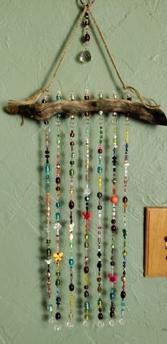 a wind chime hanging from a wooden branch with beads and glass beads on it