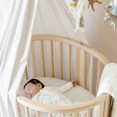 a baby sleeping in a crib next to stuffed animals