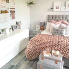 a bedroom decorated in pink and gray with pictures on the wall above the headboard