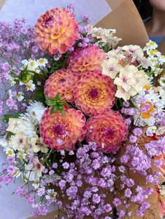 a bunch of flowers that are sitting in a vase on a table and someone is holding it