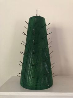 a green vase with spikes on it sitting on top of a white shelf next to a wall