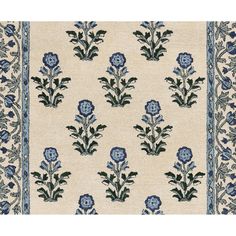 an area rug with blue flowers and leaves on white ground, in front of a beige background