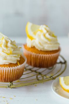 two cupcakes on a wire rack with lemon slices