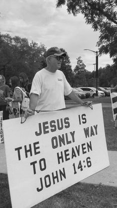 a man holding a sign that says jesus is the only way to heaven