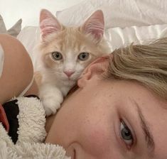 a woman laying in bed with a cat on her head and stuffed animals around her