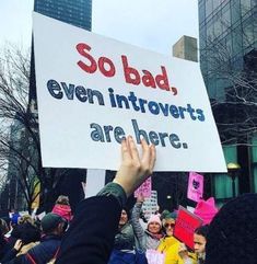 a person holding up a sign that says so bad even introverts are here