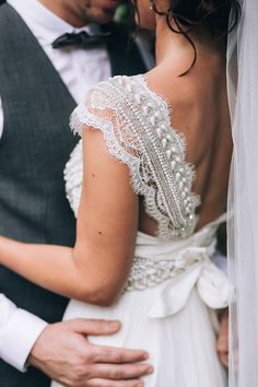 a bride and groom embracing each other in their wedding day attire with the veil pulled back