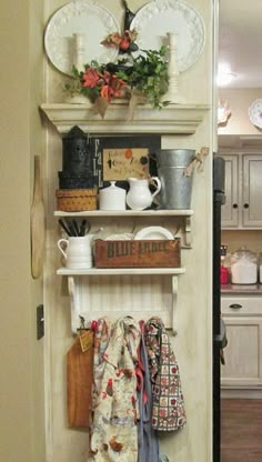 a kitchen with white cupboards filled with dishes and utensils on top of wooden shelves