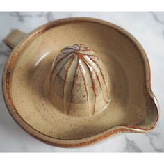 a brown and white ceramic bowl on a marble counter top, with an onion in the center