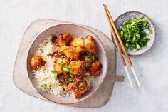 a bowl filled with rice and meat next to chopsticks on top of a table