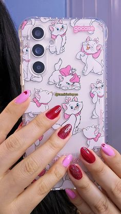 a woman's hand holding up a phone case with pink and red nail polish