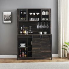 a wooden cabinet with wine glasses and bottles on it in front of a gray wall