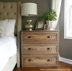 a bedroom with a bed, nightstand and lamp on it's side table in front of a window