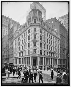 an old black and white photo of people walking in front of a building with many windows