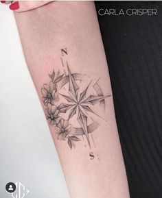 a woman's arm with a compass and flowers tattoo on the left inner arm