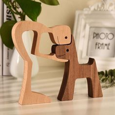 two wooden toys are standing next to each other on a table near a potted plant