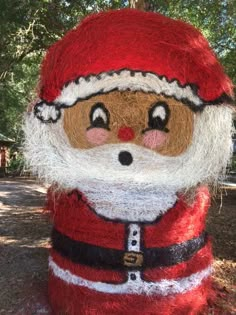 a santa clause is made out of hay and yarn, with trees in the background