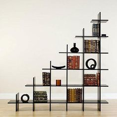 a bookshelf with many different types of books on it and a vase in the middle