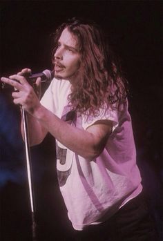 a man with long hair holding a microphone