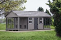 a small gray shed sitting on top of a lush green field