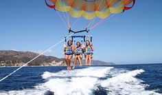 four women are parasailing in the ocean on a sunny day