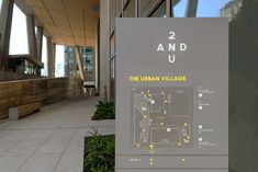 the urban village sign is in front of a building with large windows and an attached walkway