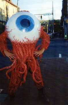 a man is holding an eyeball in the middle of his body and it's eyes are blue