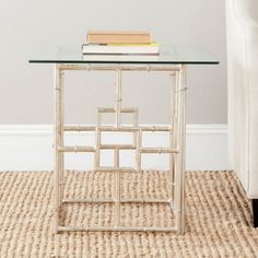 a glass table with books on it in front of a white wall and carpeted floor