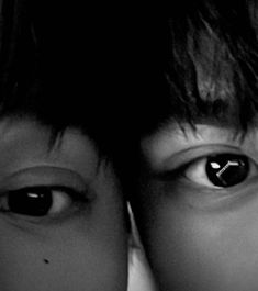 two young boys looking at the camera with their eyes close to one's face