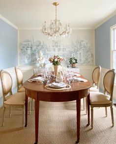 a dining room table is set with place settings and flowers in vases on top