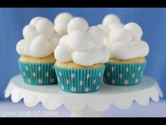 three cupcakes with white frosting and polka dots on them sitting on a cake stand