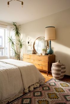 a bedroom with a bed, dresser and mirror in the corner next to a window