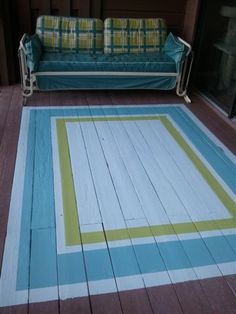 a blue couch sitting on top of a wooden floor next to a green and white rug