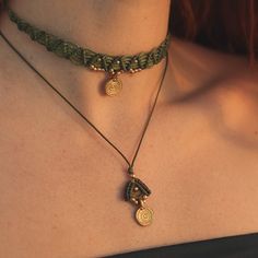 a close up of a woman wearing a necklace with two pendants on it's neck