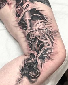 a man's leg with a clock and gears tattoo on his legs, while he is laying down