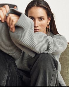 a woman is sitting on a couch with her legs crossed and looking at the camera