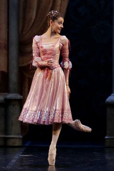 a woman in a pink dress is dancing on stage