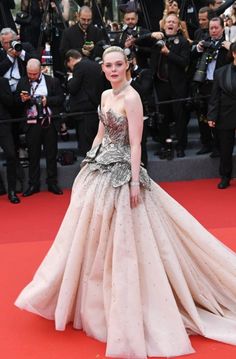 a woman standing on top of a red carpet next to photographers in front of them