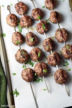 several meatballs on skewers with toothpicks and parsley sprinkled around them