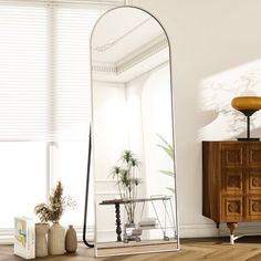 a large mirror sitting on top of a wooden floor next to a dresser and chair