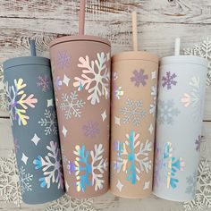 four different colored tumblers with snowflakes on them, one has a straw in it