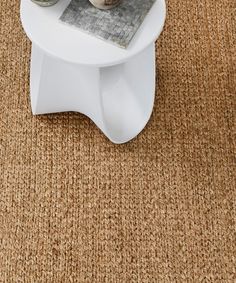 two vases sitting on top of a small white table in the middle of a carpeted room