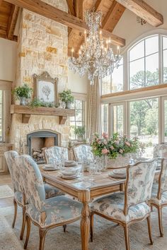 a dining room with a chandelier and table surrounded by chairs in front of a fireplace