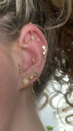 a close up of a person's ear with gold stars and moon piercings